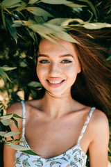 Closeup emotional  lifestyle portrait of adorable cute beautiful young cheerful coquette girl with big natural lips and blue happy eyes outdoor at nature.  Cute attractive smiling teen face.