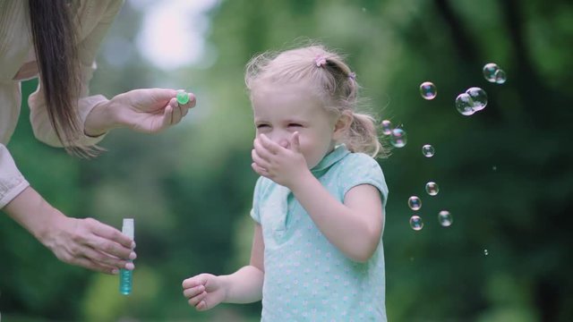 Family Having Fun. Mom And Child Making Soap Bubbles Outdoors