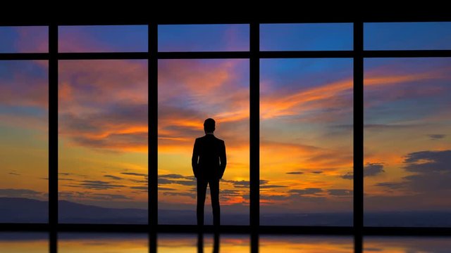 The man standing near windows on the sunrise background. time lapse
