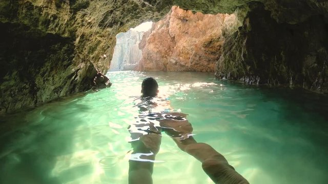 Happy young woman in bikini swimming in water cave near Ponza island coast sea in Italy
