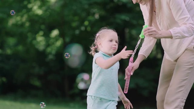 Family Having Fun. Mom And Child Making Soap Bubbles Outdoors