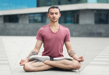 Handsome man practicing yoga in lotus pose outdoors