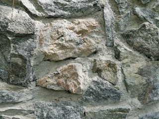 The texture of large granite stones and cement, a wall illuminated by the sun in a natural environment