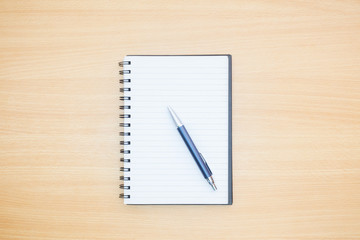 Flat lay photography. Empty notebook and a pen on a wooden table. Write memo office idea concept.