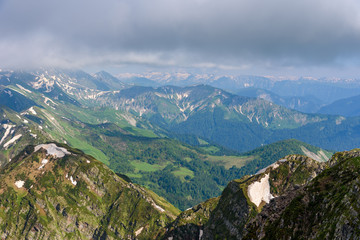 Forest in a mountain valley. Green slopes of mountains. Mountain meadow fields. Mountain ranges