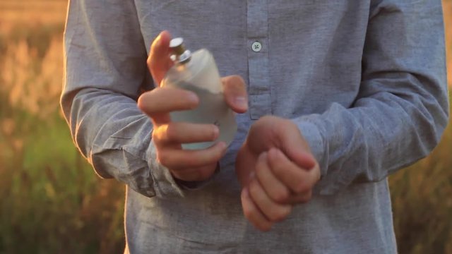 man using perfume at a beautiful sunset