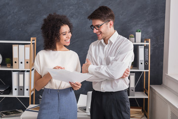 Smiling coworkers talking and discussing document in office