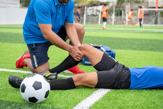 Fototapeta Footballer wearing a blue shirt, black pants injured in the lawn during the race.