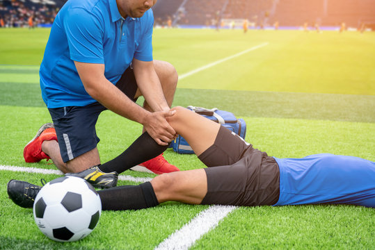 Fototapeta Footballer wearing a blue shirt, black pants injured in the lawn during the race.