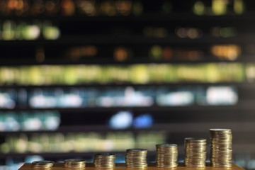 city of money. currency make metropolis go round. growing chart coin towers on wood board in front of defocused city scene at night. saving money management and business development concepts.