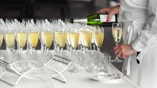 Female waiter pouring cold champagne in glasses