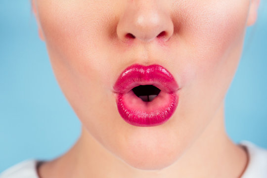 Close up view of beautiful woman lips with purple red matt lipstick studio shot. Open surprised mouth cosmetology fashion makeup concept.