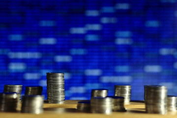 secured internet business. big coin piles in front of blue binary code computer screen. rich through savings account online.