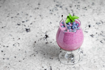 Blueberry smoothie in glass with reusable straw