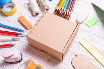 Cardboard box and stationery on wooden background, top view