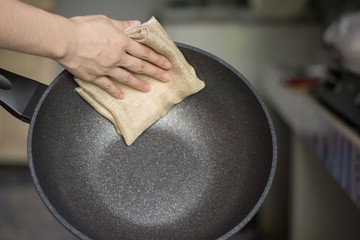 Close Up housewife hand cleaning modern pan after cooking.