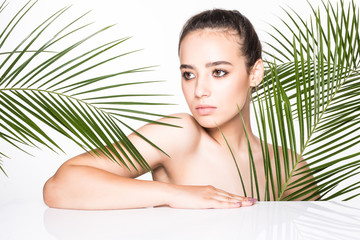 Fototapeta premium Young beauty woman with palms leaves isolated on white background. Cosmetology, spa, skincare concept.