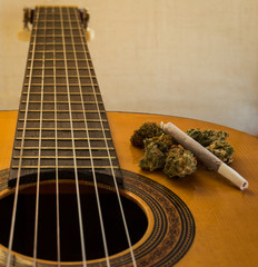 Fretboard and neck of a classical or spanish guitar with marijuana buds and joint on it. Bright...