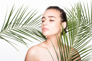 Fototapeta premium Young beauty woman with palms leaves isolated on white background. Cosmetology, spa, skincare concept.