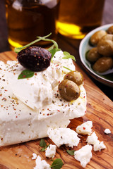 Greek cheese feta with herbs and olives on rustic table.