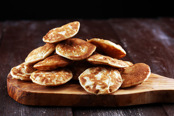 Pancakes or puffertjes with berries and maple syrup on rustic table