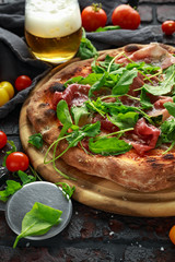 Stone Baked Pizza with prosciutto ham, arugula, parmesan and mozzarella cheese, beer