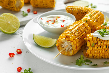 Grilled sweet corn with white mexican sauce, chilli and lime. healthy summer food