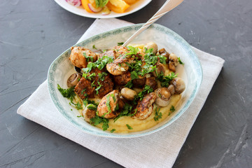 mashed potatoes with fried mushrooms and chicken on a side dish with tomatoes.