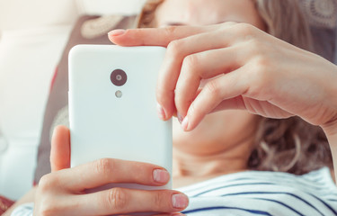 a woman lays on the bed and holds the phone in her hands