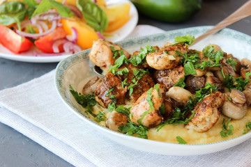 mashed potatoes with fried mushrooms and chicken on a side dish with tomatoes.