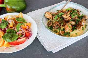 mashed potatoes with fried mushrooms and chicken on a side dish with tomatoes.
