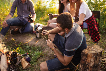pleasant guy is cutting a wooden stick while camping with friends. hunting concept. tool for camping . close up top view photo