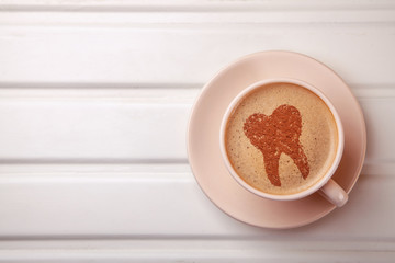Cup of coffee with tooth on foam. Coffee spoils teeth and makes them yellow. Morning coffee