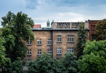 Fototapeta premium Old and rustic apartment house with many windows and lush trees in Krakow, Poland