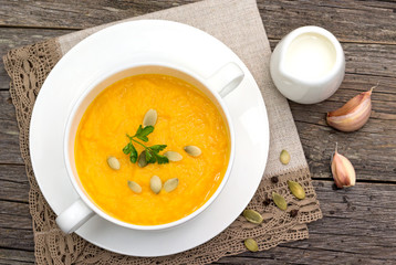 Pumpkin soup in a saucepan on a wooden table.
