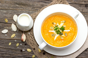 Pumpkin soup in a saucepan on a wooden table.