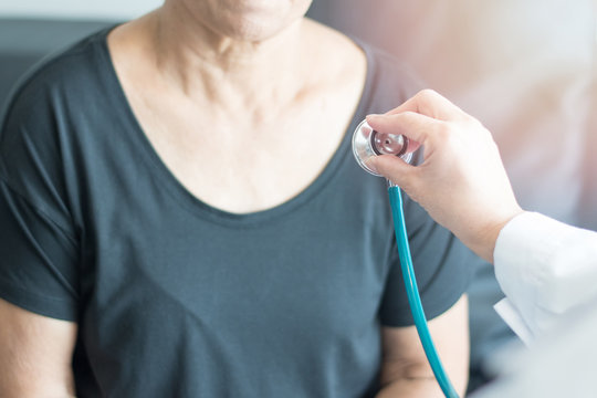 Doctor hand with stethoscope check up elderly woman people. Old aging female seeing medical physician in clinical healthcare hospital.