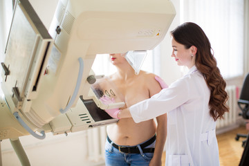 Side view of the young happy breast specialist who is carrying out the ultrasound examination of the breast of a patient in her office