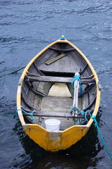 Small yellow wooden row boat on lake in Norway