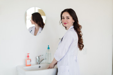 The young pretty smiling breast specialist washing her hands in her office