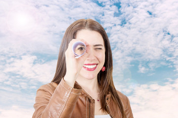 smiling woman looking in a spyglass made with a roll