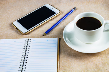 Flat lay, top view office table desk. Workspace with blank board, office supplies, pencil, green leaf, and coffee cup on white background.