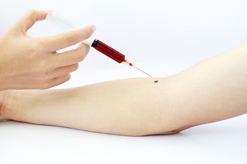 Female hand holding a syringe with blood red in the syringe. Man has arm dripping blood.