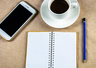 Flat lay, top view office table desk. Workspace with blank board, office supplies, pencil, green leaf, and coffee cup on white background.