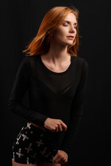 Portrait of young and sexy redhead girl in dark studio.