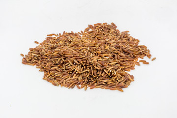 A pile of uncooked red rice against a white background