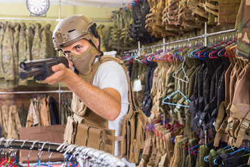 adult guy in military equipment with weapon in army shop