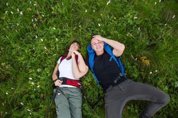 Young couple of hikers with backpack on grass have fun
