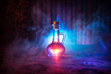 Antique and vintage glass bottles on dark foggy background with light. Poison or magic liquid...