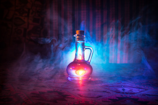 Antique and vintage glass bottles on dark foggy background with light. Poison or magic liquid concept. - Powered by Adobe